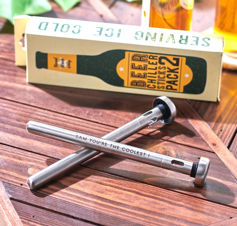 Pode incluir: Dois palitos de refrigerar cerveja de a&ccedil;o inoxid&aacute;vel com uma ponta de borracha preta. Os palitos est&atilde;o cruzados um sobre o outro. O palito superior tem o texto "SAM YOU'RE THE COOLEST!" gravado. A embalagem dos palitos de refrigerar cerveja est&aacute; no fundo. A embalagem &eacute; verde e amarela e diz "SERVING ICE COLD" e "BEER CHILLER STICKS PACK 2".