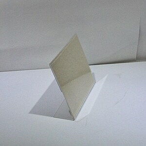 May include: A clear acrylic sign holder with a rectangular base and a slanted display surface.