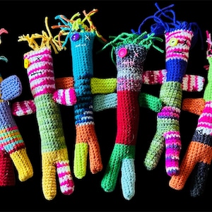 May include: Seven colorful crocheted dolls with different facial expressions and hair styles. The dolls are made of yarn in various colors, including red, green, blue, yellow, and pink.