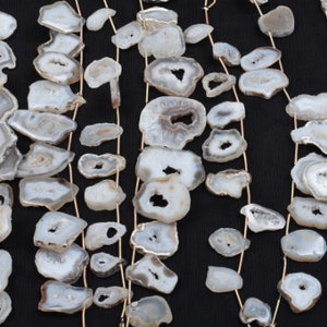 May include: A strand of white agate gemstone beads with a natural crystal pattern. The beads are strung on a thin wire and are arranged in a cascading pattern.