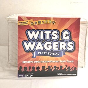 May include: A boxed party game titled "Wits & Wagers" with a red and orange background. The game box features the text "WITS & WAGERS PARTY EDITION" in large, white and blue letters. The box also states "HISTORY'S MOST AWARD-WINNING PARTY GAME!"