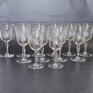 May include: A collection of clear, stemmed wine glasses. Each glass features a starburst design etched into the bowl. The glasses are arranged on a dark surface, showcasing their elegant shape and intricate detailing.
