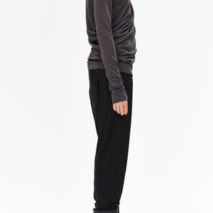 Puede incluir: Un jersey de cuello alto gris oscuro con mangas largas y silueta ajustada. El jersey se combina con pantalones negros y botines negros.