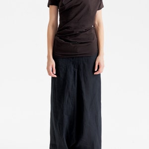 May include: A brown draped top with short sleeves and a pair of black wide-leg pants.