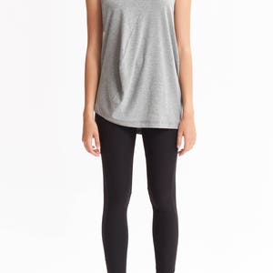 May include: A gray sleeveless top with a cowl neck and a black pair of leggings.