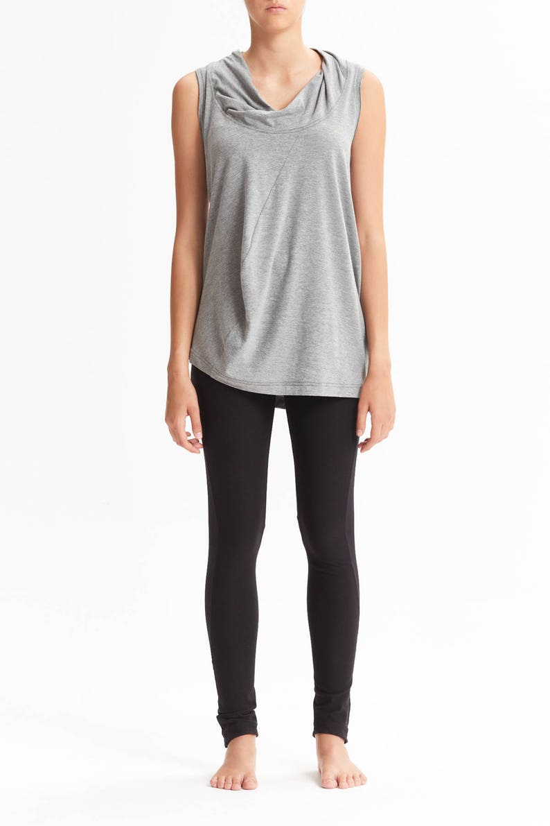 May include: A gray sleeveless top with a cowl neck and a black pair of leggings.
