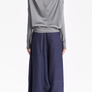 May include: A gray long-sleeved top with a cowl neck and a pair of dark blue wide-leg pants.