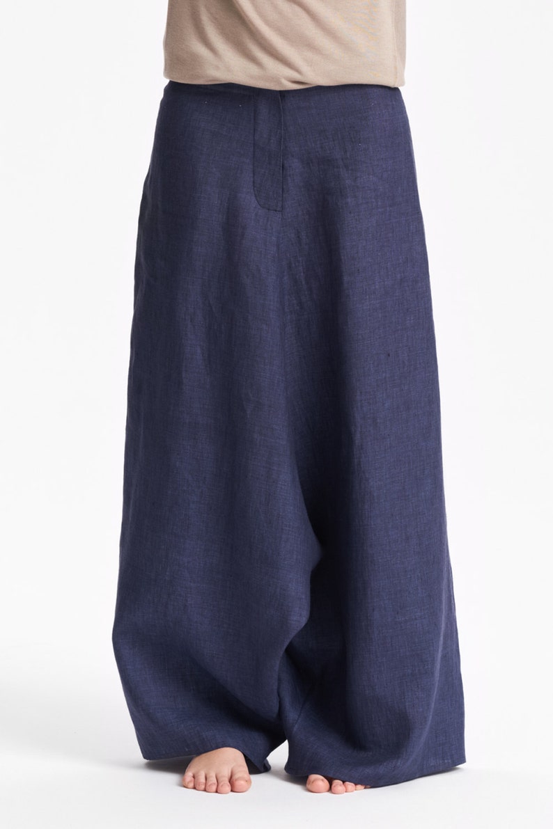 May include: Wide-leg trousers in a deep navy blue color featuring a high-waisted design with a central vertical seam detail. The garment is crafted from a textured fabric and falls in a loose, relaxed silhouette that extends down to the ankles.