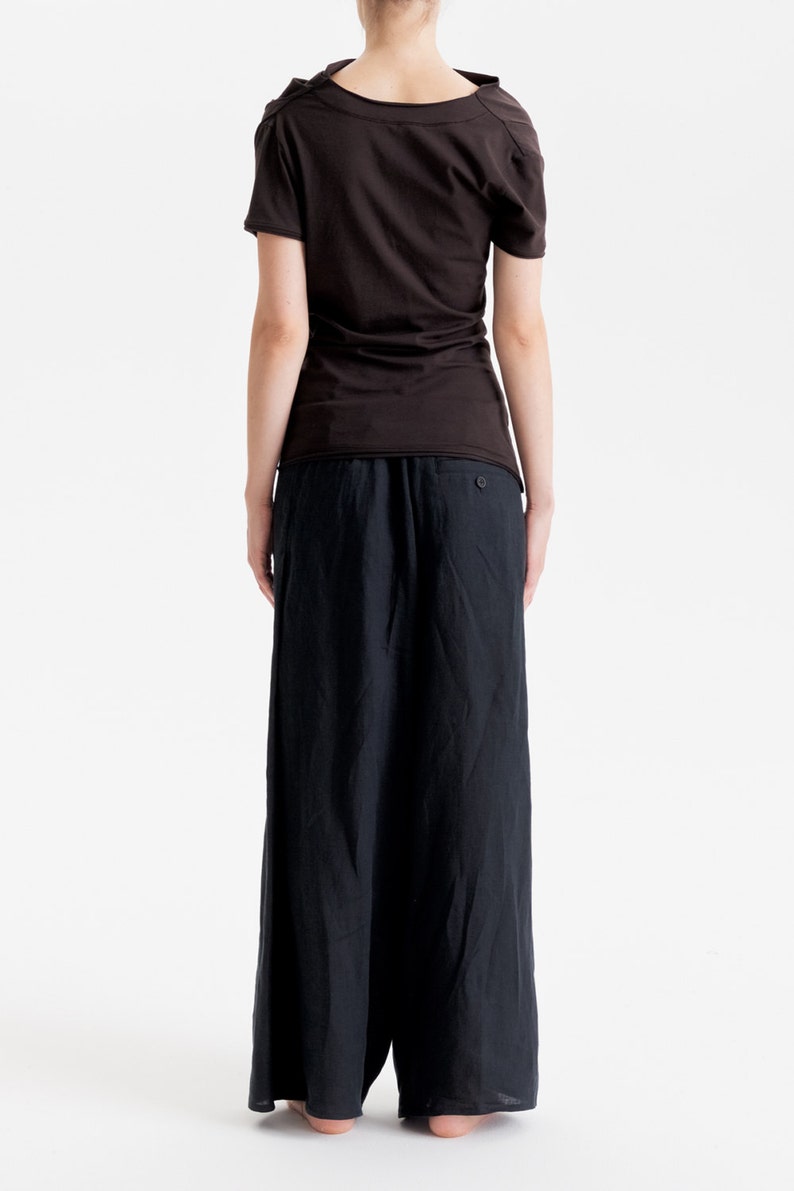 May include: A black, short-sleeved, scoop neck top with a loose fit and a black pair of wide-leg pants.