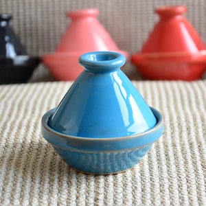 May include: A blue ceramic tagine with a lid. The tagine is a traditional Moroccan cooking pot.