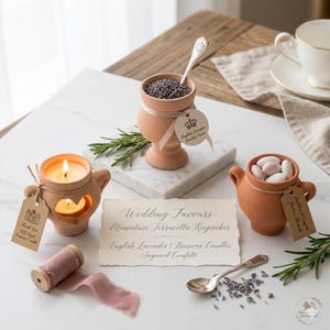Könnte beinhalten: Eine Auswahl an Miniatur-Terracotta-Andenken, darunter ein Kerzenhalter mit brennender Kerze, eine Vase mit Lavendel und ein Topf mit gezuckerten Mandeln. Eine Spule mit rosa Band und ein Vintage-Löffel sind ebenfalls zu sehen. Hochzeitsthema.