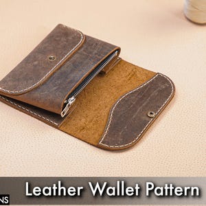 May include: Open brown leather wallet with a zipper closure and white stitching. The wallet is partially open, revealing a lighter brown interior. The text "Leather Wallet Pattern" is displayed below the wallet.