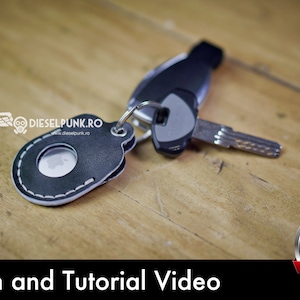 May include: A black leather key fob with a white stitch detail and a round cutout. The fob is attached to a silver key ring with a silver key. The key fob is on a wooden surface.  Pattern and Tutorial Video. PDF Download.