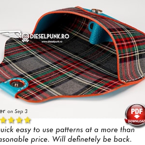 May include: A red, green, and black plaid fabric wallet with a blue lining and orange stitching. The wallet is open and the inside is visible. The wallet is made of leather and has a snap closure.
