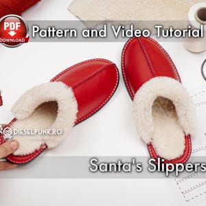 Può includere: Ciabatte di Babbo Natale in pelle rossa con fodera in pelliccia sintetica bianca. Le ciabatte sono su una superficie bianca con un motivo e un rotolo di filo bianco. Il testo "Santa's Slippers" è visibile nell'immagine.