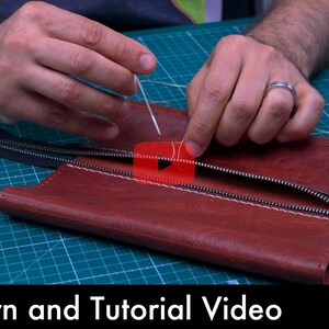 Może przedstawiać: Osoba przyszywa zamek błyskawiczny do brązowego sk&oacute;rzanego portfela. Portfel leży na zielonej macie do cięcia. Tekst "Pattern and Tutorial Video" znajduje się na dole obrazu.