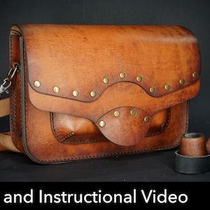 Könnte beinhalten: Eine hellbraune Lederschultertasche mit gewellter Klappe, Messingnieten und passendem Lederriemen. Neben der Tasche steht eine hölzerne Tabakpfeife in einem kleinen schwarzen Lederhalter. Der Text PDF DOWNLOAD Pattern and Instructional Video ist sichtbar.
