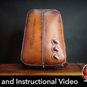 Può includere: Uno zaino in pelle marrone con finitura sfumata, bordi con cuciture bianche, una cucitura centrale verticale e tre dettagli cilindrici sporgenti color rame sul lato destro. Il testo DIESELPUNKRO è impresso sulla superficie anteriore.