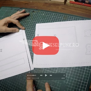 May include: A close-up of a white paper pattern with the text "A2" and a series of dotted lines. The pattern is on a green cutting mat.