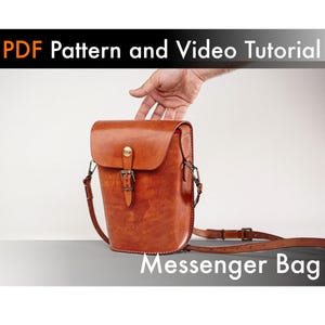 May include: A tan leather messenger bag with a flap closure, a brass buckle, and an adjustable shoulder strap. The image includes the text PDF Pattern and Video Tutorial and Messenger Bag. The bag features visible stitching and metal hardware.