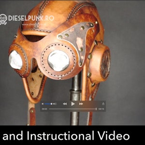 Puede incluir: Un casco de aviador de cuero marrón con una visera de metal y gafas transparentes. El casco está en un soporte y tiene una correa para la barbilla. El texto "DIESELPUNK.RO" es visible en el casco.