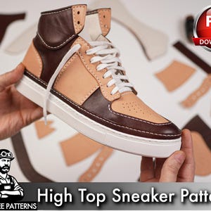 Puede incluir: Una zapatilla de caña alta con un diseño bicolor que combina paneles de cuero color canela y marrón oscuro. El calzado incluye cordones blancos, una suela de goma blanca con laterales texturizados y costuras blancas visibles en las uniones.