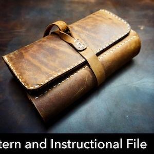 Op de afbeelding: Een bruine leren oprolbare etui met zichtbare witte stiksels langs de randen en een leren riemsluiting. Het item wordt gepresenteerd als een digitaal patroon en instructiebestand, aangegeven door een rood PDF-downloadicoon.