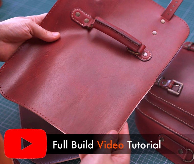 May include: A close-up of a burgundy leather satchel with a handle and strap attachments. The satchel is held open, revealing the interior. The text "Full Build Video Tutorial" is displayed in white on a black background.