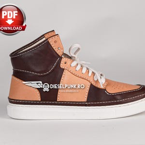 Puede incluir: Zapatillas de cuero marr&oacute;n y beige de ca&ntilde;a alta con cordones blancos y suela blanca. Las zapatillas tienen un dise&ntilde;o de ala en el lateral y el texto "DIESELPUNK.RO" en el lateral.