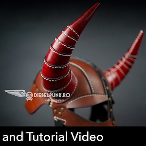 May include: A brown leather helmet with two red horns. The horns are made of multiple layers of leather stitched together. The helmet has a stitched design and metal accents. The text "Pattern and Tutorial Video" is at the bottom of the image. A red button with the text "PDF DOWNLOAD" is in the lower right corner.