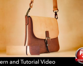 May include: A two-tone leather shoulder bag featuring a light tan flap and a dark brown body. The bag includes a metal buckle closure on the front, visible stitching along the edges, and an adjustable leather strap with metal hardware clips.