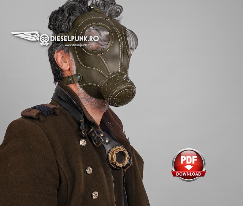 May include: A person wearing a green leather gas mask with a clear plastic eye shield. The mask has a stitched design and is worn over a brown jacket with a decorative metal piece.