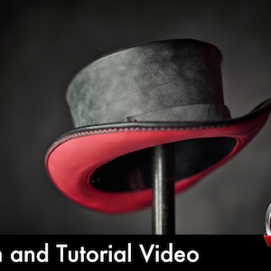 Puede incluir: Un sombrero de copa con una corona gris oscuro texturizada y una parte inferior del ala de color rojo vibrante. El sombrero se muestra sobre un soporte. El texto inferior dice Pattern and Tutorial Video, junto a un icono rojo de PDF.