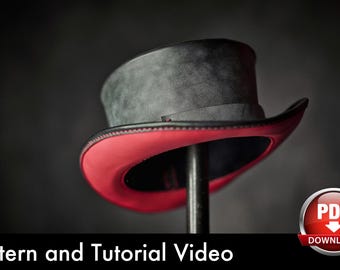 May include: A top hat with a textured dark gray crown and a vibrant red underside on the brim. The hat features black stitching along the edge of the brim and a dark band around the base of the crown. The text Pattern and Tutorial Video is visible.