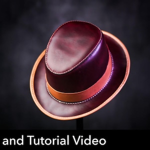 May include: A deep burgundy leather fedora hat featuring a smooth finish, a tan leather hat band, and visible white stitching along the crown and brim edges. The image includes a red circular icon with the white text PDF DOWNLOAD.