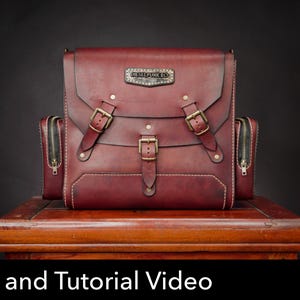 May include: A deep red leather bag featuring three brass-toned buckles on the front flap, side pockets with metal zippers, and a rectangular metal plate with the text DIESELPUNK RO. The bag includes visible stitching and a structured design.