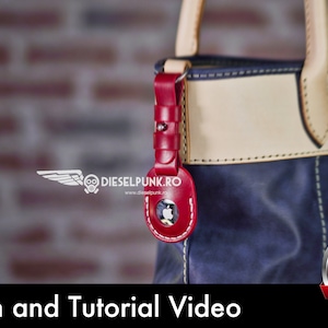 May include: A close-up of a blue leather tote bag with a red leather keychain featuring an apple logo. The bag has a cream-colored leather trim and stitching. The image includes the text "Pattern and Tutorial Video" and a download button labeled "PDF".