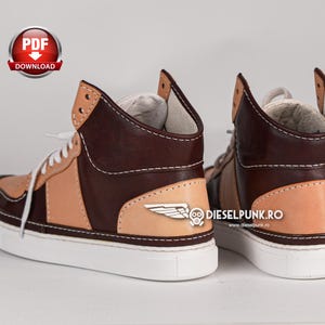 Puede incluir: Un par de zapatillas de cuero marr&oacute;n y beige de ca&ntilde;a alta con suela blanca. Las zapatillas tienen un dise&ntilde;o de ala en el lateral y el texto "dieselpunk.ro" y "www.dieselpunk.ro" en el lateral.