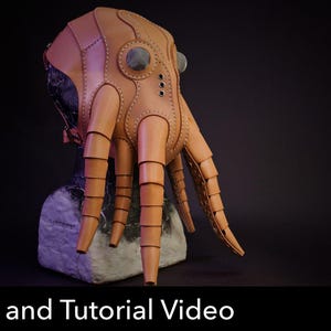 Op de afbeelding: Een beige leren masker in de vorm van een octopushoofd met gesegmenteerde tentakels, ronde oogopeningen en zichtbare stiksels langs de panelen. Het masker staat op een getextureerde basis met een rood icoon met de tekst PDF DOWNLOAD.