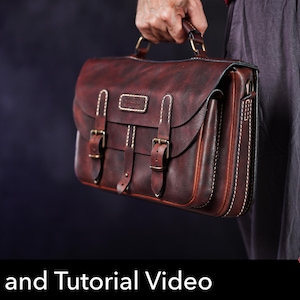 May include: A dark reddish-brown leather satchel featuring a top handle, two front straps with brass-toned metal buckles, and visible white stitching along the edges. The bag has a rectangular flap closure and a structured design for carrying items.