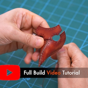 May include: A brown leather plague doctor mask component featuring visible stitching along the center seam and eye openings. The text "Full Build Video Tutorial" is displayed in a red and black rectangular graphic overlay.