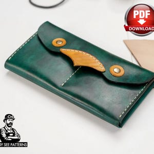 May include: A handcrafted, dark green leather wallet with a unique design. The wallet features a flap closure with two brass-colored rivets and a tan leather accent. White stitching outlines the edges. The wallet is a PDF download.