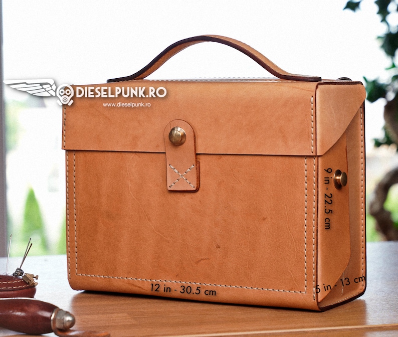 May include: A brown leather briefcase with a top handle, measuring 30.5 cm by 22.5 cm by 13 cm. The briefcase has a brass clasp and stitching details.