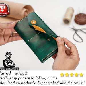 May include: A handcrafted, dark green leather wallet with a contrasting tan interior and a snap closure. The wallet is held open, revealing the interior. The image includes sewing tools and a PDF download icon.