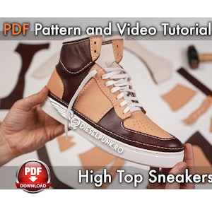 Può includere: Un paio di sneakers alte con tomaia in pelle marrone e beige e suola bianca. Le sneakers sono tenute da una mano e sono circondate da pezzi di pelle, suggerendo un progetto fai-da-te. Il testo "PDF Pattern and Video Tutorial" e "High Top Sneakers" è visibile nell'immagine.