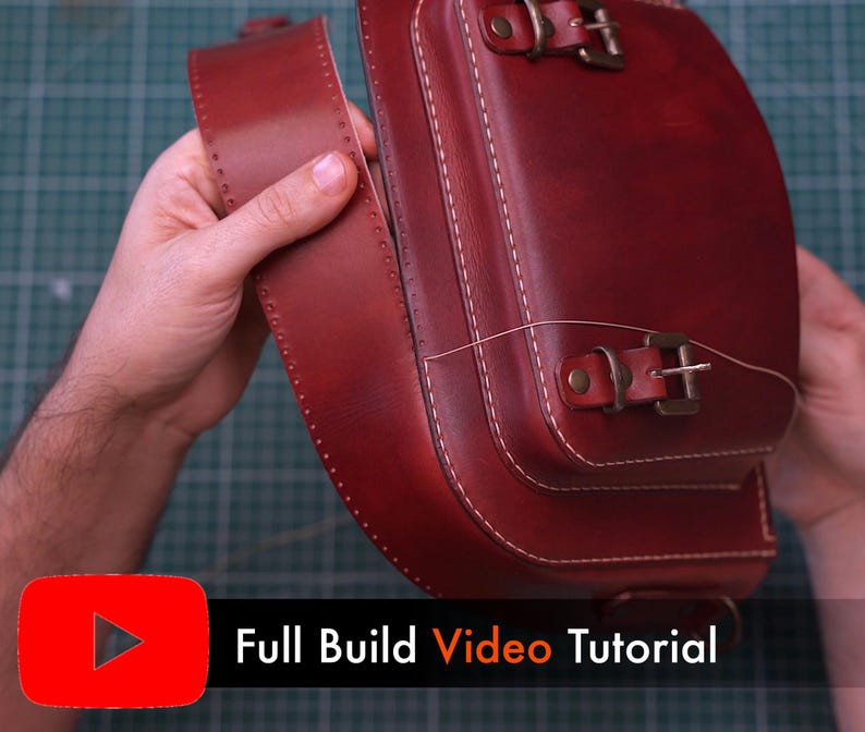 May include: A handcrafted, burgundy leather satchel with white stitching and brass buckles. The bag features a flap closure and a shoulder strap. The text "Full Build Video Tutorial" is displayed on the bottom of the image.