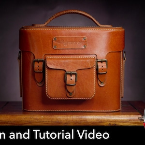 May include: A tan leather bag with a top handle, a front pocket with a buckle closure, and two side buckles. A rectangular leather patch with the embossed text DIESELPUNK is centered on the upper front. The bag features visible stitching.