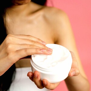 Person scooping vegan body and hand cream from jar moisturising lotion for soft hydrated skin cruelty free skincare