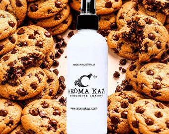 May include: A white spray bottle with a black cap is centered in a photo surrounded by chocolate chip cookies. The bottle has the text "AROMA KAZ EXQUISITE LUXURY" and "MADE IN AUSTRALIA". The website address www.aromakaz.com is also visible.