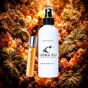 Op de afbeelding: Een witte sprayfles en een kleine glazen rollerfles, beide met het label AROMA KAZ. De witte fles bevat de tekst MADE IN AUSTRALIA, AROMA KAZ EXQUISITE LUXURY en www.aromakaz.com. De kleinere fles bevat een amberkleurige vloeistof.